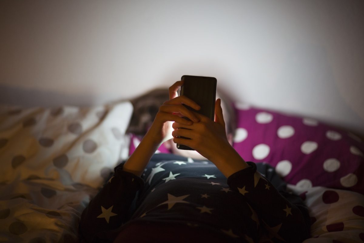 Child holding a phone in bed