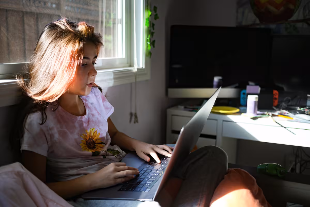 Young woman working on a laptop in a bedroom